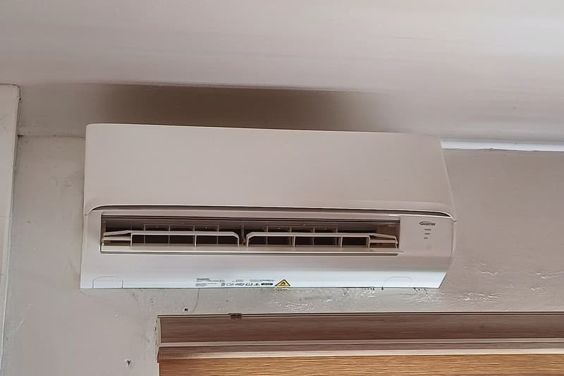 Technician checking water drain line and condensate tray on split AC