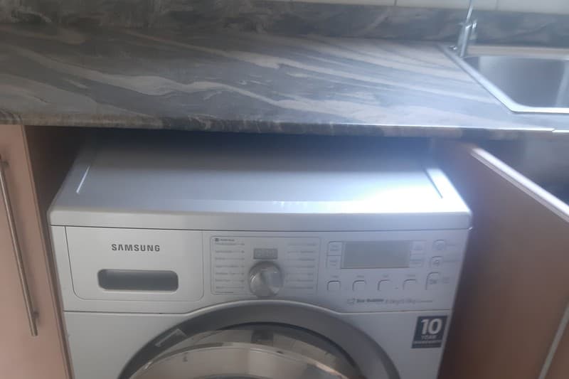Technician testing 16A power socket and control panel on washing machine